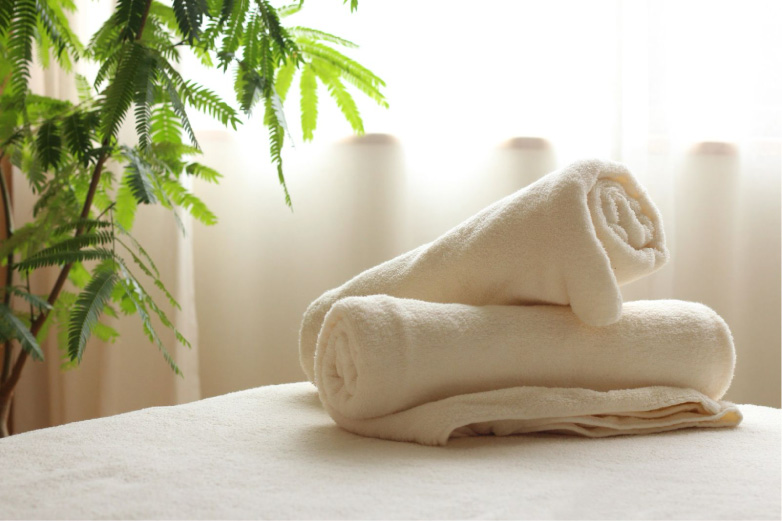 清潔感のある施術台と、ラストーンセラピーで使用される丁寧に整えられたタオル